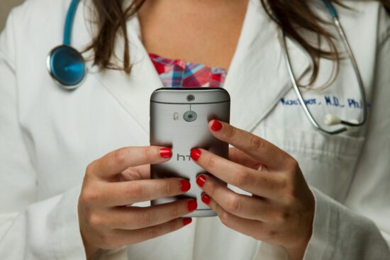 Doctor Holding Cell Phone. Cell phones and other kinds of mobile devices and communications technologies are of increasing importance in the delivery of health care. Photographer Daniel Sone